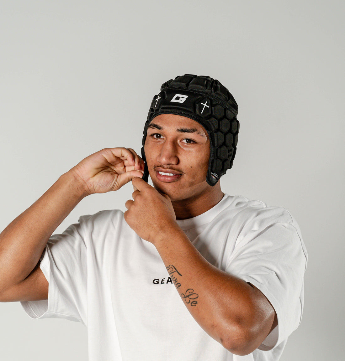 GearFit Legacy rugby headgear in black with cross design, lifestyle photo